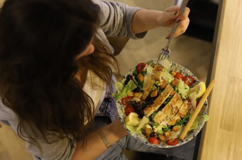 Overhead view of a woman eating a chicken salad balancing health with deliciousness.