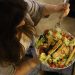 Overhead view of a woman eating a chicken salad balancing health with deliciousness.
