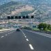 Long highway with cars traversing through rocky hills under blue skies, perfect travel scene.